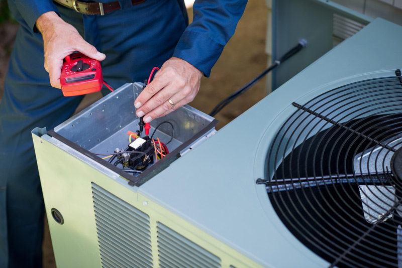 A technician performing air conditioner maintenance on an AC unit.